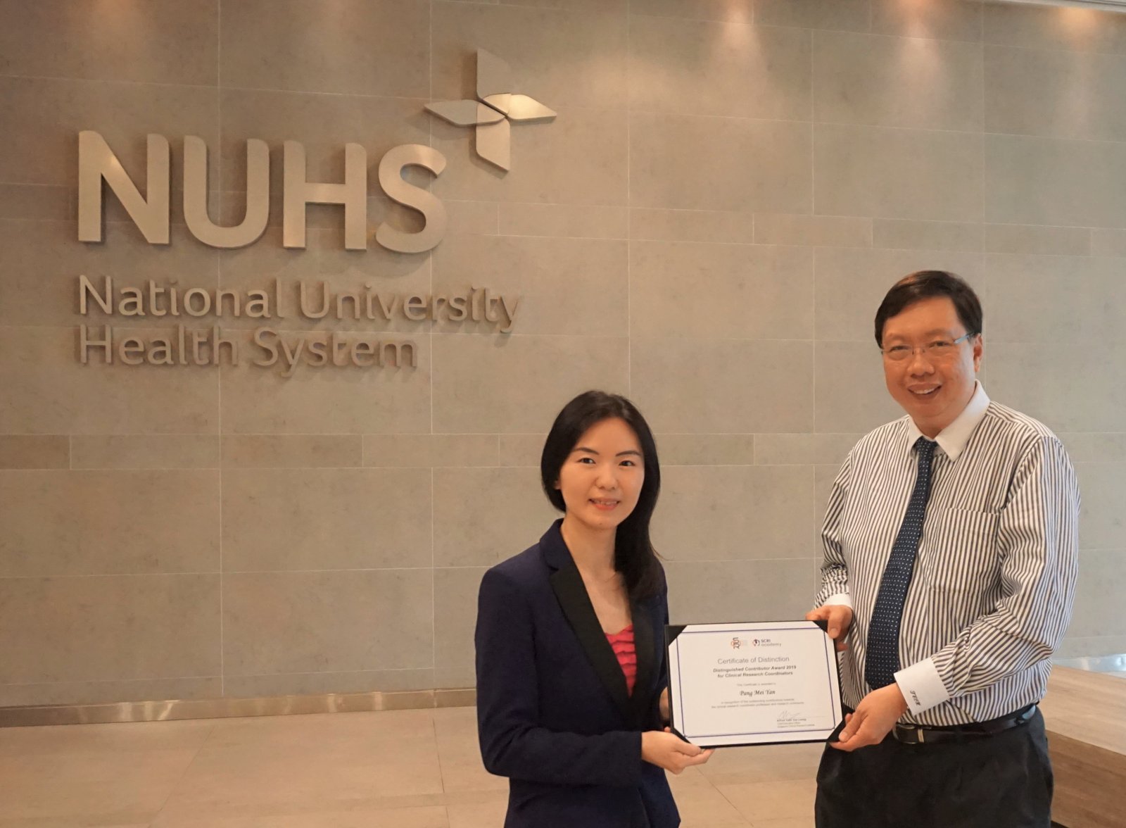 Associate Professor Teoh Yee Leong, CEO of Singapore Clinical Research Institute (right) presenting the inaugural Distinguished Contributor Award to Ms Pang Mei Yan, the winner of The Distinction Award.