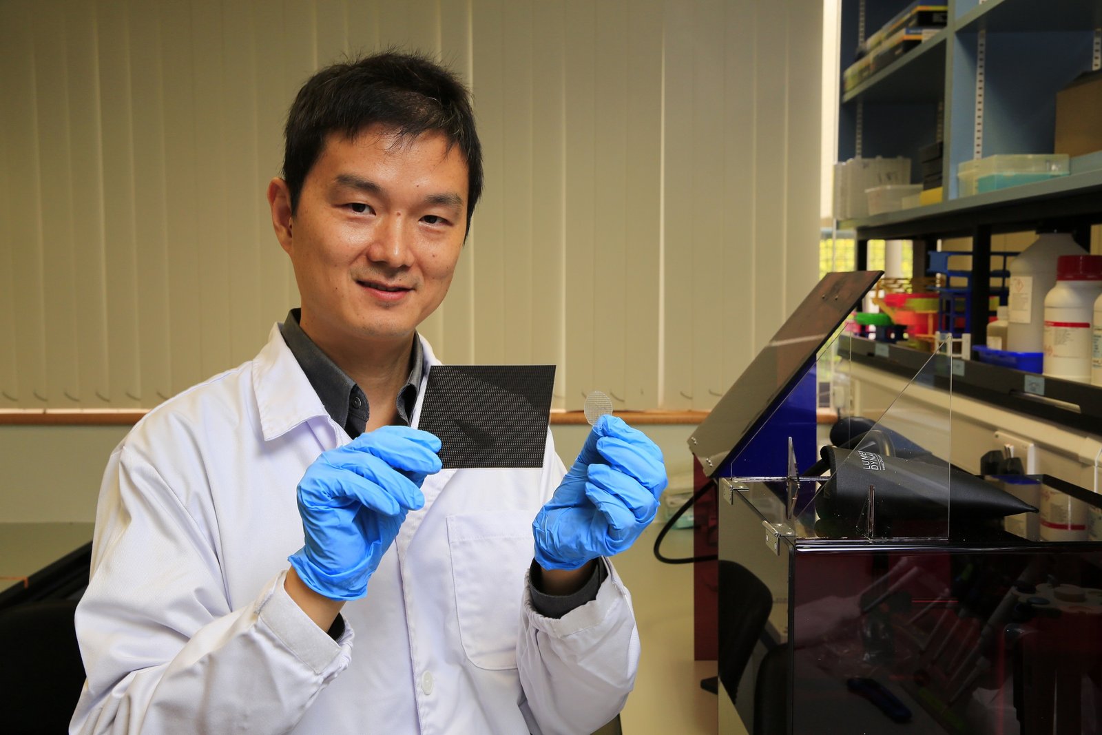 Lead researcher Dr Kang Lifeng at NUS holding a microneedle patch in his left hand, and a photomask in his right hand. Photo Courtesy: National University of Singapore